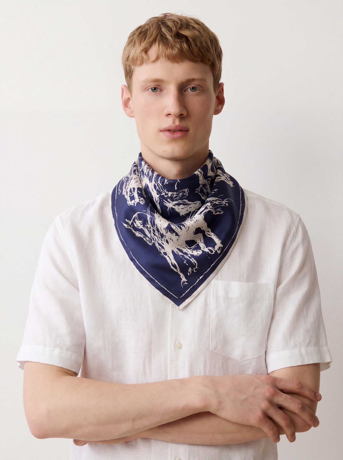 Man wearing a white shirt and a blue scarf with a dog pattern on a plain background