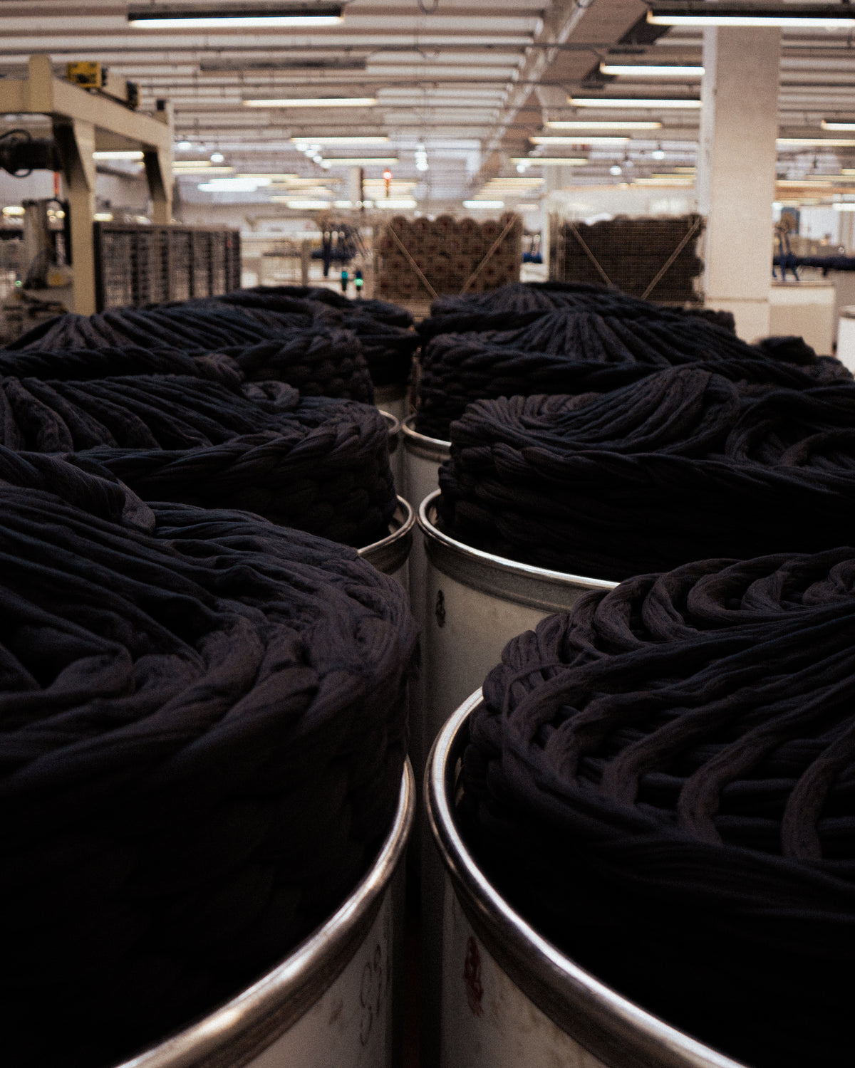 Dyed yarn coiled in steel cans on the finishing floor of a mill