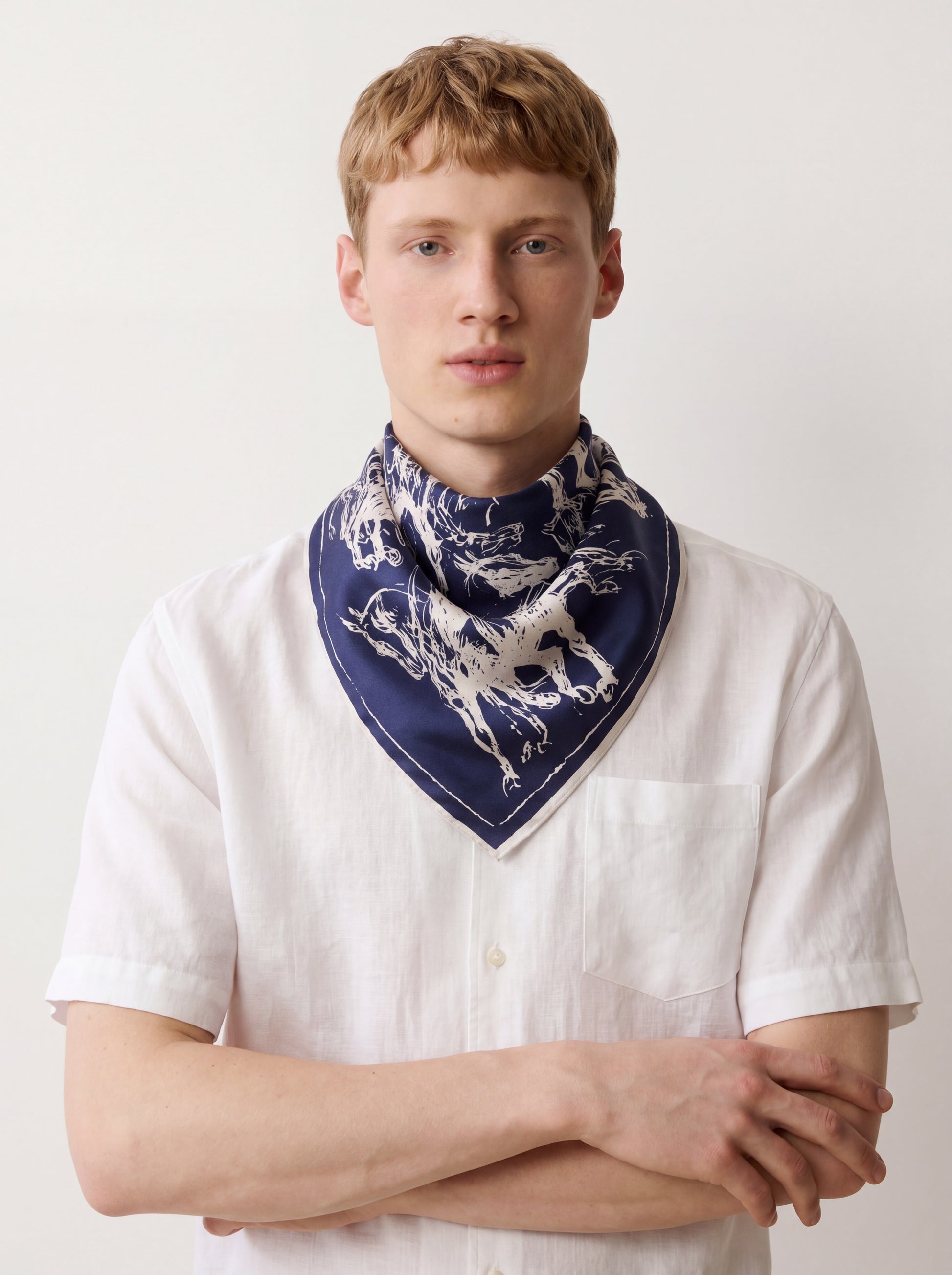 Man wearing a white shirt and a blue scarf with a dog pattern on a plain background