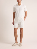 Man wearing a white polo shirt and shorts set on a plain background