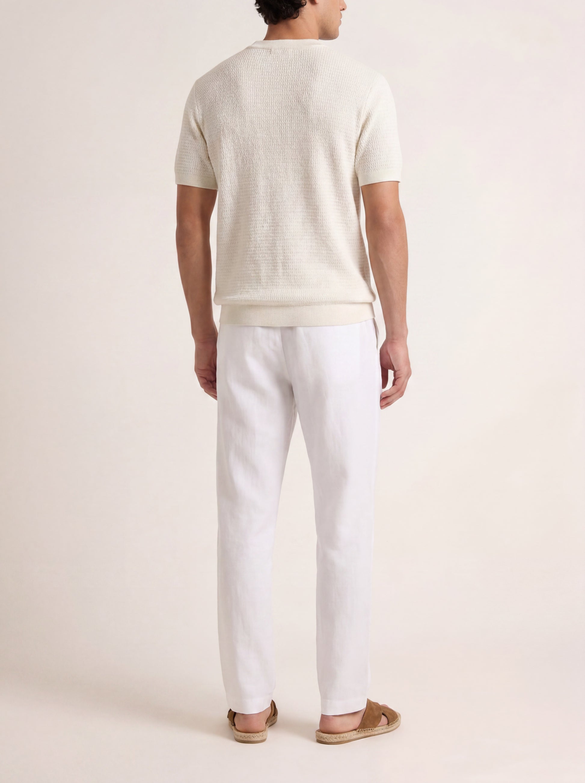 Person wearing a white t-shirt and pants on a plain background