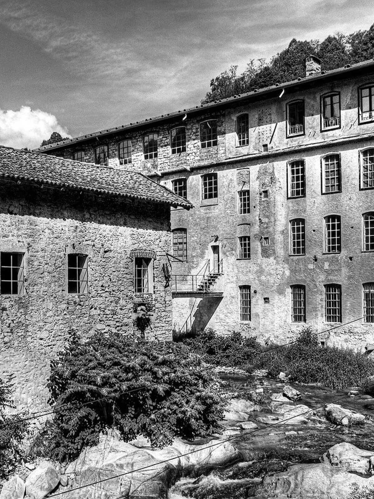 A stone mill building above the river in the Biella valley
